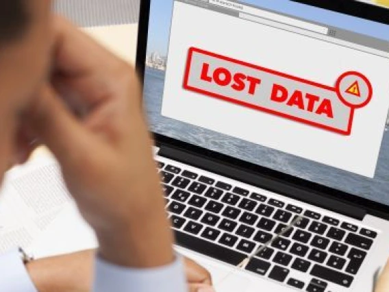 Person frustrated in front of a laptop reading "lost data" on the screen.