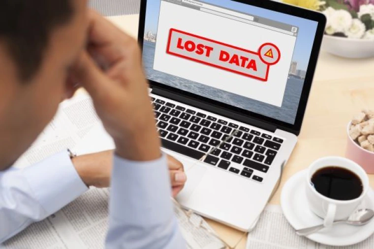 Person frustrated in front of a laptop reading "lost data" on the screen.